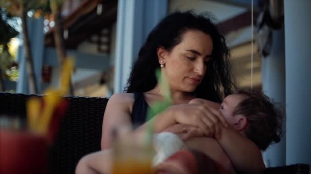 Mamá con un niño al aire libre, amamantándolo, dándole leche materna a un niño que arrulla. . — Vídeos de Stock