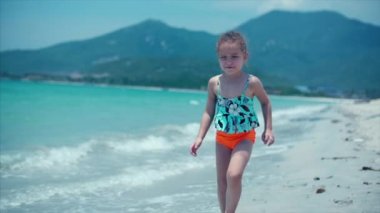 Sevimli küçük kız sahilde annesi kocaman bir kucak ve öpücük için doğru çalışır. Atış kapatın. Stok görüntüleri