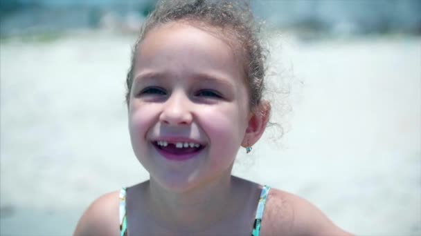 Портрет чарівної дівчинки в купальнику. Дитина стоїть на пляжі посміхаючись, дивлячись на камеру . — стокове відео