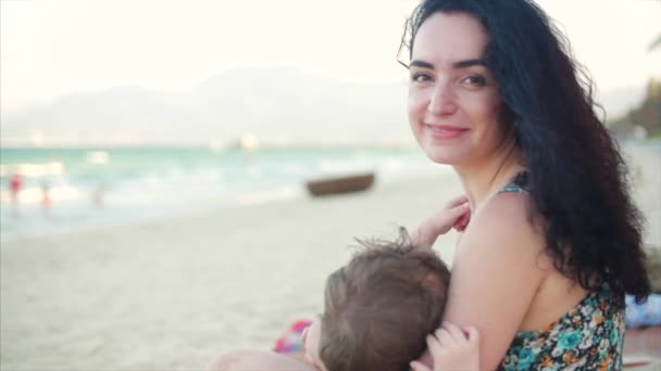 Portret van een charmante moeder met een baby in haar armen. Moeder met baby genieten van frisse lucht, moeder is borstvoeding de baby en lulling hem. — Stockvideo