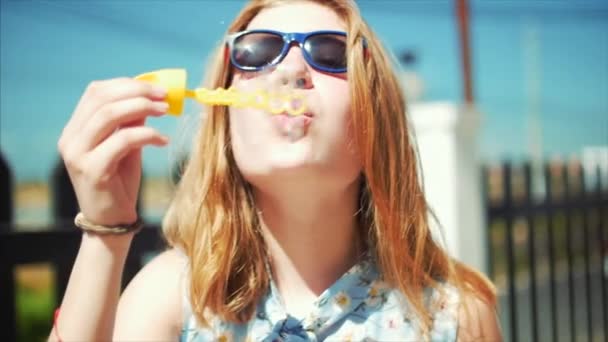 즐거운 10 대 소녀 백인 모습을 웃 고, 카메라를 보고 웃 고 여름 야외에서 비누 거품을 불고. 클로즈업입니다. 증권 영상. — 비디오