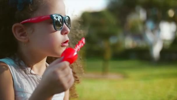 Happy child blowing soap bubbles in park. Slow motion. Stock footage. — Stock Video