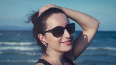 Kamera, rüzgarda saç isteyen genç kadının yakın çekim.