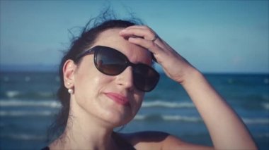 Kamera, rüzgarda saç isteyen genç kadının yakın çekim.