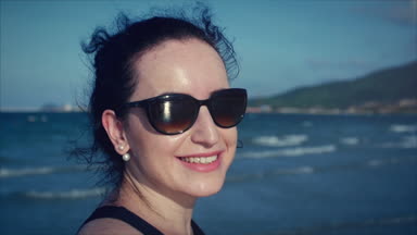 Kamera, rüzgarda saç isteyen genç kadının yakın çekim.