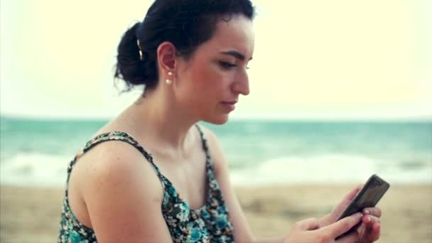 Молодая белая женщина с помощью смартфона у моря . — стоковое видео