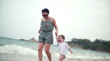 Genç aile, anne ve çocuk sahil boyunca yürüyor. Mutlu aile deniz kıyısında yürüyüş.