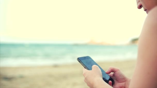 Jeune femme caucasienne utilisant smartphone par la mer . — Video