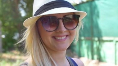 Bir güzel görünüm ve doğal ile harika gülümseyen kadın yapmak kamera ve saçlarını hareketli rüzgar bakarak.