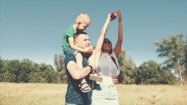 Familia feliz, mamá, papá e hijo están caminando en la naturaleza, lanzando una serpiente de aire. Material de archivo . — Vídeo de stock