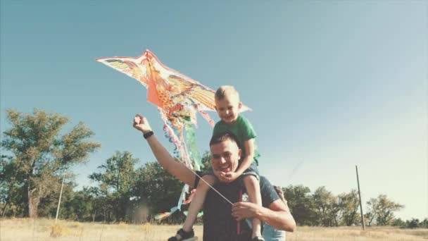Familia feliz, mamá, papá e hijo están caminando en la naturaleza, lanzando una serpiente de aire. Material de archivo . — Vídeos de Stock