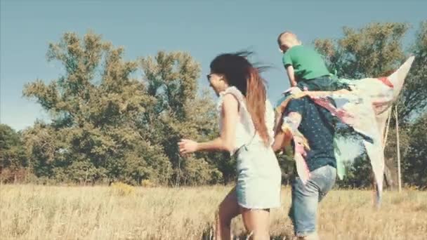 Familia feliz, mamá, papá e hijo están caminando en la naturaleza, lanzando una serpiente de aire. Material de archivo . — Vídeos de Stock