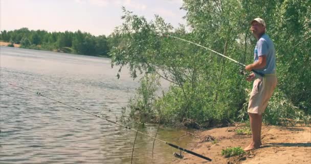 Feliz padre e hijo están pescando, el hijo ayuda a su padre a sacar el pescado capturado, lleva el receptor de peces. Familia feliz . — Vídeos de Stock