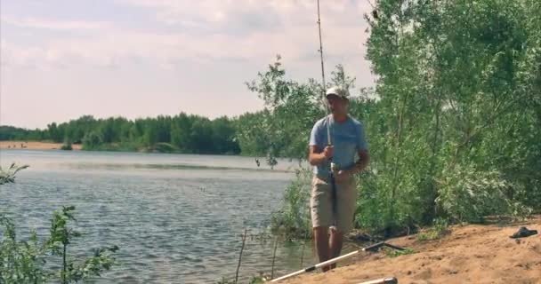 Feliz padre e hijo están pescando, el hijo ayuda a su padre a sacar el pescado capturado, lleva el receptor de peces. Familia feliz . — Vídeos de Stock