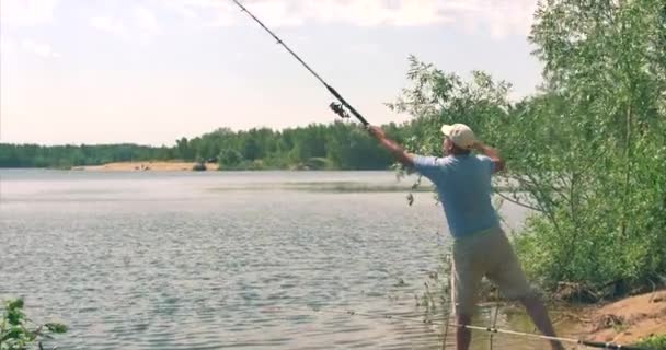 Hombre pescador lanza un aparejo de pesca en el agua . — Vídeos de Stock