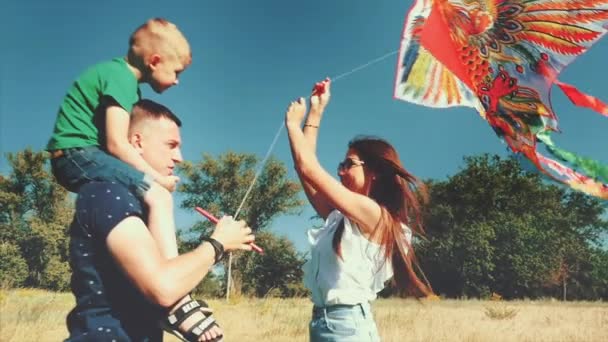 Familia feliz, mamá, papá e hijo están caminando en la naturaleza, lanzando una serpiente de aire. Material de archivo . — Vídeo de stock