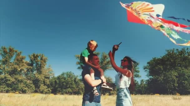 Familia feliz, mamá, papá e hijo están caminando en la naturaleza, lanzando una serpiente de aire. Material de archivo . — Vídeos de Stock