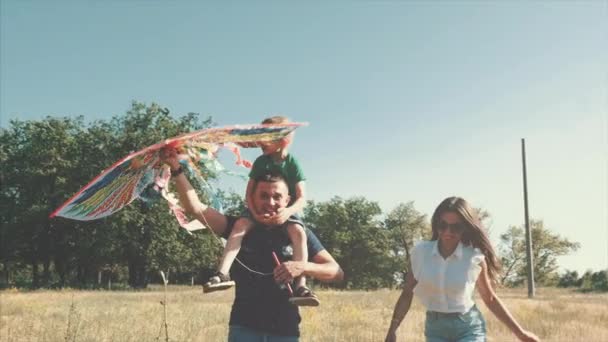 Familia feliz, mamá, papá e hijo están caminando en la naturaleza, lanzando una serpiente de aire. Material de archivo . — Vídeos de Stock