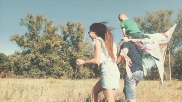 Familia feliz, mamá, papá e hijo están caminando en la naturaleza, lanzando una serpiente de aire. Material de archivo . — Vídeo de stock