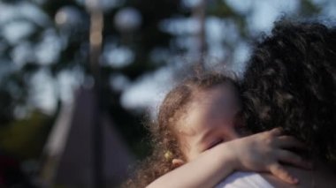 Kızı sokakta annesinin kollarında ve onu kocaman bir kucak, öpüşme ve kamera, göz gülümseyen verir yakın çekim. Ağır çekim.