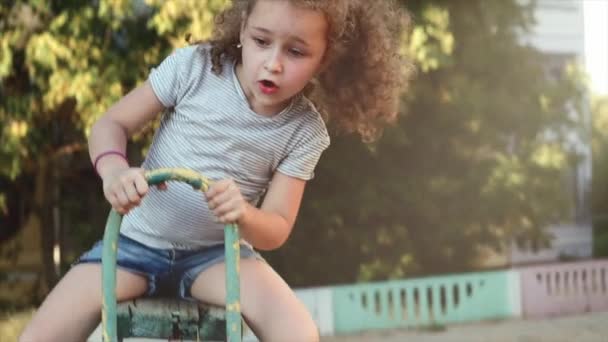 Glad ung liten flicka spinning i en gunga och leende — Stockvideo