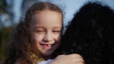 Kızı sokakta annesinin kollarında ve onu kocaman bir kucak, öpüşme ve kamera, göz gülümseyen verir yakın çekim. Ağır çekim.