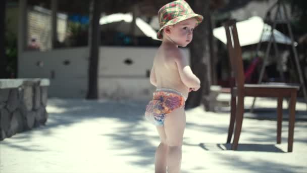 Ευτυχισμένο αγόρι σε ένα καπέλο που περπατά κατά μήκος στην άμμο. — Αρχείο Βίντεο