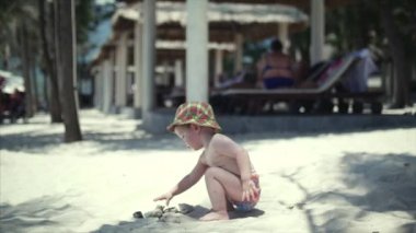 Kumsalda oynarken bir şapkalı mutlu çocuk.
