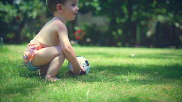 En två-år-gammal pojke gillar att spela fotboll i parken, springa och sparka bollen. — Stockvideo
