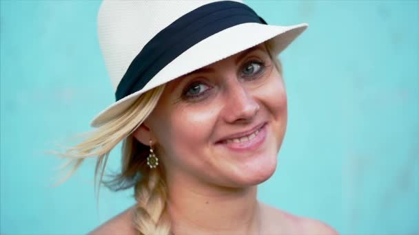 Portrait of a beautiful caucasian woman appearance, blonde in a white hat with blue ribbon, outdoors, smiling looking at camera. — Stock Video