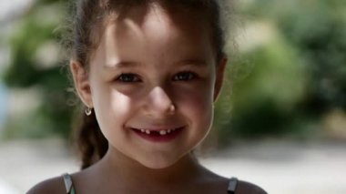 Güzel bir gülüşün ve kamera, mutlu seyir yeşil gözlü kıvırcık saçlı mutlu küçük kız gülümseyerek.