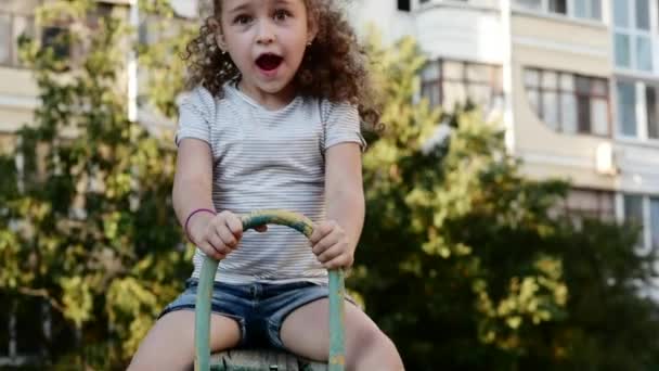 Jovem menina feliz girando em um balanço e sorrindo — Vídeo de Stock