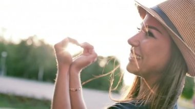 Eller güzel kadın ile kalp şekil verme gün batımı kız aşk sembolü jest turuncu güneş parlama ile gidiyor.