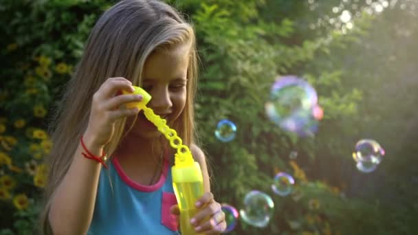 Happy child blowing soap bubbles in park. Slow motion. Stock footage. — Stock Video