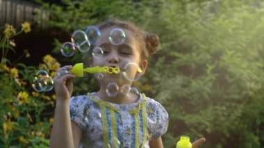 Mutlu çocuk parkında sabun köpüğü üfleme. Ağır çekim. Stok görüntüleri.