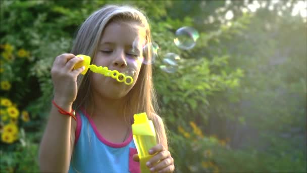 Gelukkig kind blazen van zeepbellen in park. Slow-motion. Beeldmateriaal. — Stockvideo