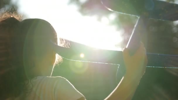 Criança feliz corre com um avião de brinquedo em um fundo de pôr do sol . — Vídeo de Stock