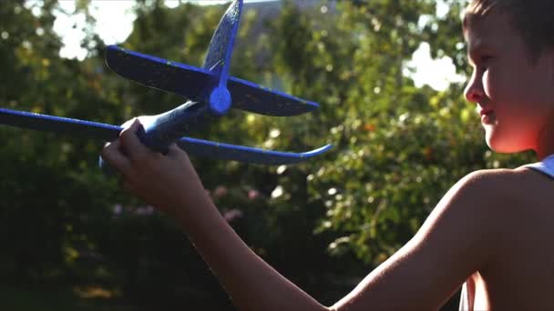 Glückliches Kind, das mit Flugzeug in den Händen spielt und vor dem Hintergrund des Sonnenuntergangs läuft. — Stockvideo