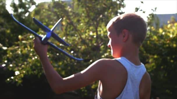 Criança feliz brincando com avião nas mãos de correr em um fundo pôr do sol . — Vídeo de Stock