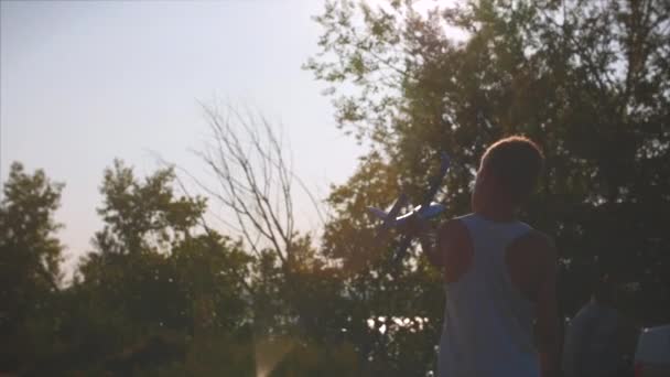 Gelukkig kind spelen met vliegtuig in handen van een zonsondergang achtergrond waarop. — Stockvideo