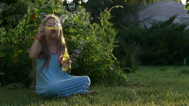 Slow motion van een Happy Kaukasische meisje blazen van zeepbellen op een zonnige dag. Concept gelukkige kindertijd of childrens games in de natuur. — Stockvideo