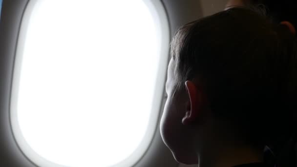 El niño mira por la ventana del avión. . — Vídeo de stock