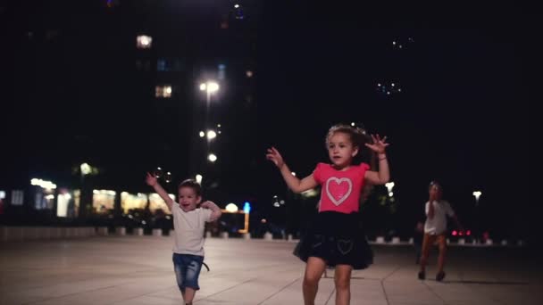 Fröhliche Kindergruppe, die im Park mit Seifenblasen spielt. Kinder fangen Seifenblasen am Abend im Park. — Stockvideo