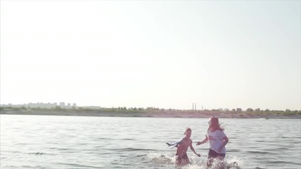 Glückliche und unbeschwerte Kindheit. Kinder spielen mit einem Hund, laufen am Sand entlang, lachen, spielen auf dem Fluss, starten ein Spielzeugflugzeug. — Stockvideo