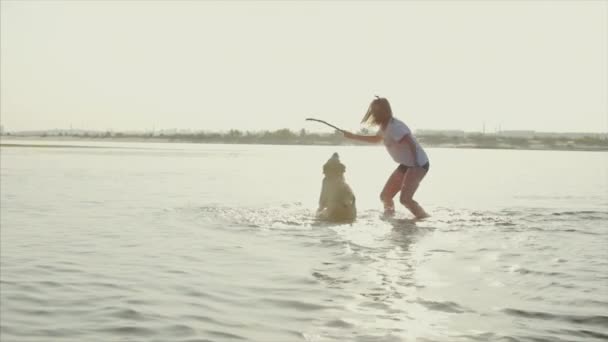 Glückliche und unbeschwerte Kindheit. Kinder spielen mit einem Hund, laufen am Sand entlang, lachen, spielen auf dem Fluss, starten ein Spielzeugflugzeug. — Stockvideo