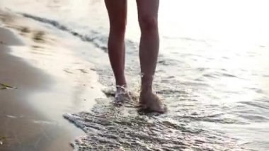 Üzerinden aşağıda kadınsı bacaklar görüntülemek, sahilde yürüyüş sahil, güzel erkek, bir kadın yürüyor. Denizin kadın ayaklarını yıkar.