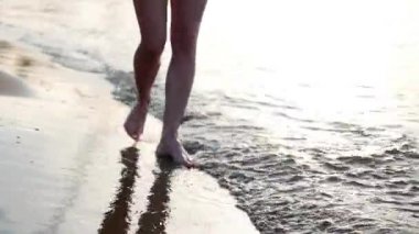 Üzerinden aşağıda kadınsı bacaklar görüntülemek, sahilde yürüyüş sahil, güzel erkek, bir kadın yürüyor. Denizin kadın ayaklarını yıkar.