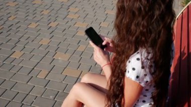 Güzel genç kadın kentsel mutlu yaşam tarzı yaşayan bir tezgah şehir sokaklarında oturan akıllı telefon teknoloji app kullanarak bir beyaz görünüm.