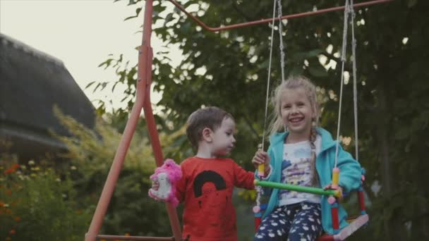 Двоє щасливих гарненьких дітей тримають руки і грають на свіжому повітрі . — стокове відео