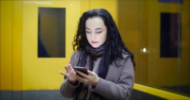 Çekici kadın şenlikli ışıklar gece şehrin arka plan üzerinde sokaklarda yürürken cep telefonunuzun.